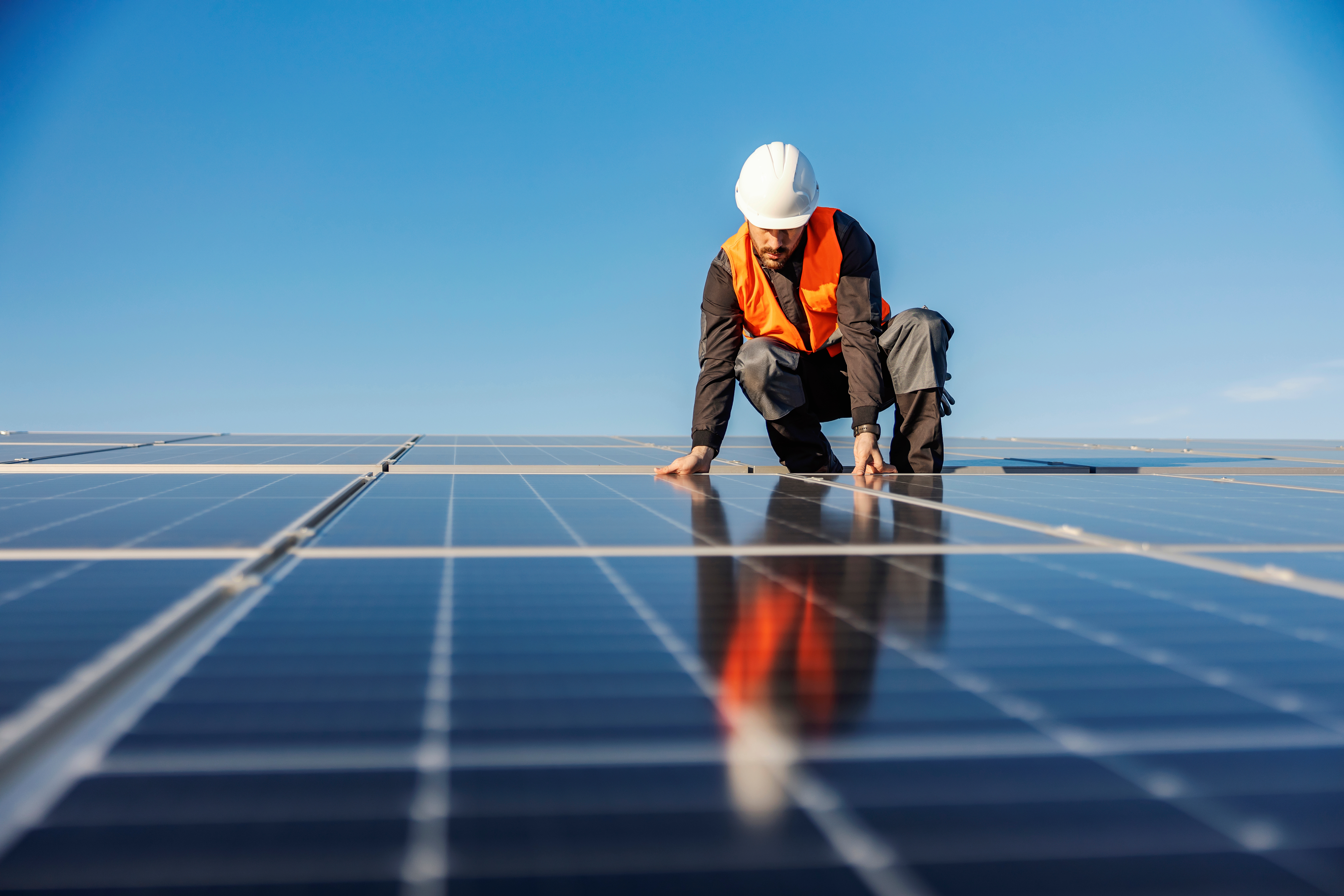Das Bild zeigt einen Mann, der auf einem Photovoltaikdach arbeitet.