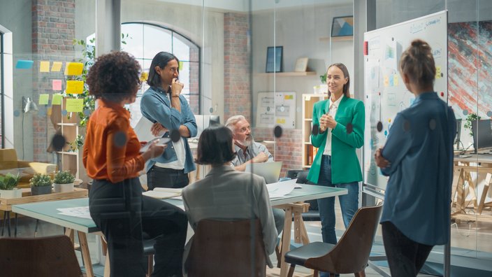 Sechs Personen in einer Besprechung in einem modernen Büro. 
