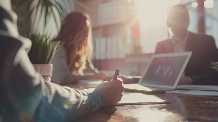 Angebote und Lösungen Ein Team sitzt an einem Tisch. In der Mitte steht ein Laptop.