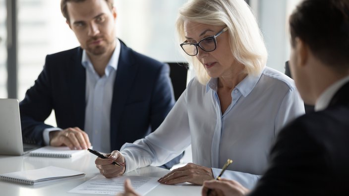 Verwaltung und Abrechnung von Firmenpensionen Eine Frau und zwei Arbeitskollegen sitzen an einem Tisch.