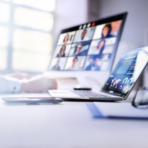 Das Bild zeigt zwei Laptops auf einem Tisch stehend und es läuft ein Onlinemeeting