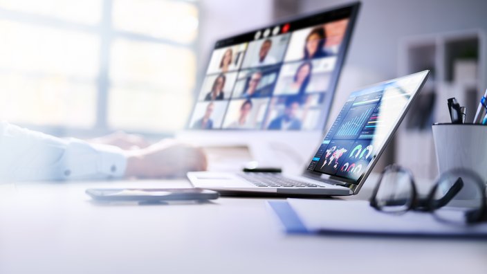 Das Bild zeigt zwei Laptops auf einem Tisch stehend und es läuft ein Onlinemeeting